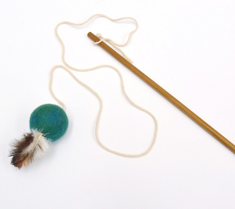 Cat toy with a green ball and feather on a string, attached to a wooden stick on a white background