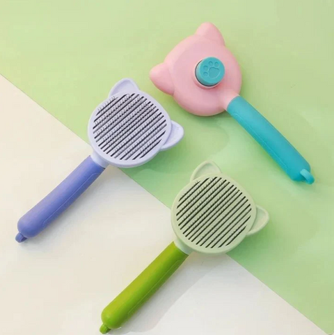 Three pet grooming brushes with colorful handles on a green and beige background