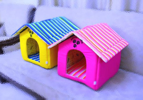 Two colorful dog houses, one pink and one multicolored, on a snowy surface.