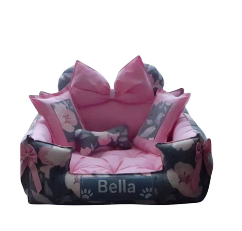 Pink and black pet bed with decorative bows and 'Bella' branding on a white background