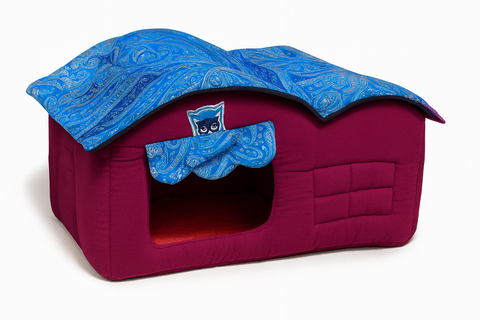 Pink pet bed with blue cover featuring a cat design on a white background