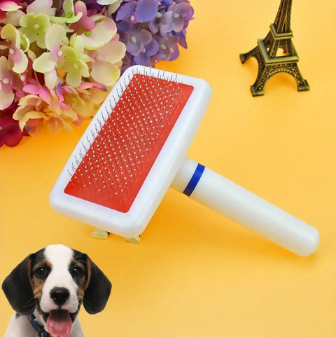 Pet grooming brush with red surface and white handle on a yellow background with flowers and Eiffel Tower figurine.