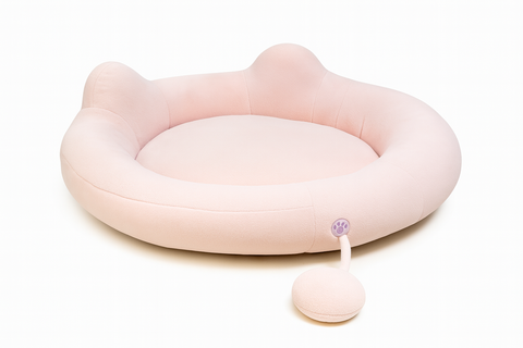 Pink pet bed with a paw-shaped pull tab on a white background